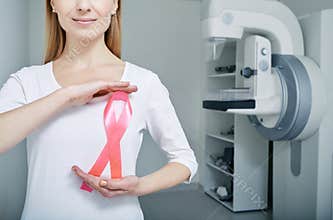 A woman holding breast cancer awareness ribbon urging women to have regular breast screening and mammogram. Mammography
