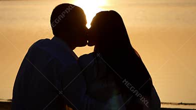 Silhouette young couple kissing on the bank of a