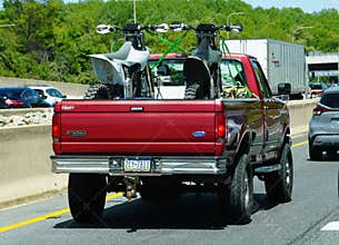 Newark, Delaware, U.S - May 5, 2026 - A red Ford F-250 hauling two dirt bikes in the truck bed while traveling on I-95 North