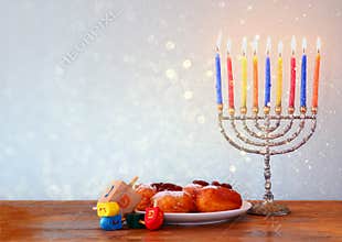 Jewish holiday Hanukkah with menorah, doughnuts over wooden table. retro filtered image