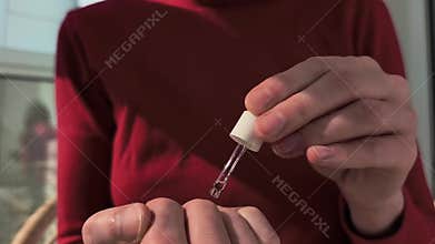 Hand applies liquid serum with dropper in close up. Careful