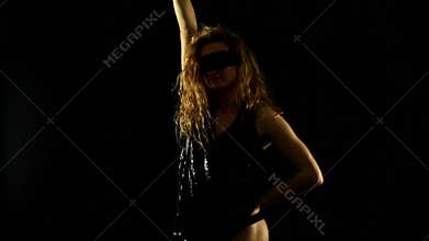blonde woman with shining black top and masque dancing in the dark
