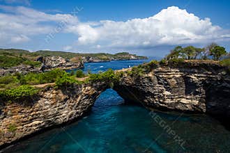Tropical Rock Arch Framed by Blue Ocean and Green Hills