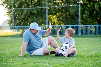 Dad and son having fun while practicing football outdoors.