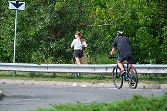 Cyclist And Female Jogger Sharing Urban Bicycle Route