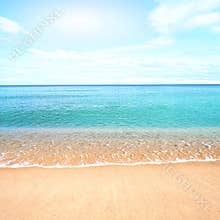 Sandy beach with calm water against blue skies.