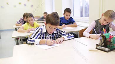 Group of school kids writing test in classroom