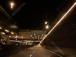 Empty illuminated roadway inside dark modern tunnel with warm ceiling lights