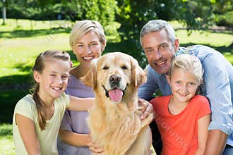 Happy family smiling at the camera with their dog