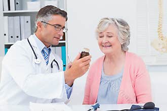 Doctor showing medicine bottle to female patient