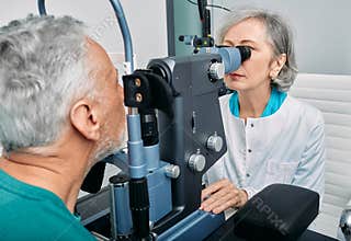 Senior man getting eye exam at ophthalmology clinic with optometrist. Ophthalmology for older people