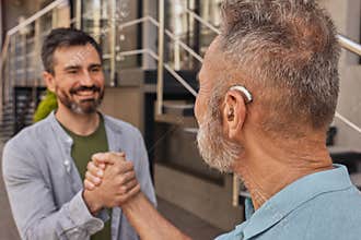 Elderly man with hearing impairment uses hearing aid to communicate