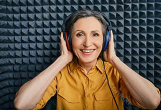 Hearing loss treatment. A mature woman wearing audiometry headphones while hearing test and audiogram in special audio room