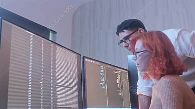Programmers working at night analyzing code on monitors in a modern office