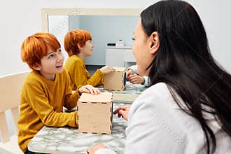 A pediatric speech and language therapy. Cute boy doing game exercises with his private therapist during a session of