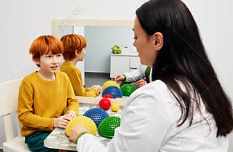 Sensory integration therapy. Boy of autism spectrum disorder with therapist using hedgehog half balls