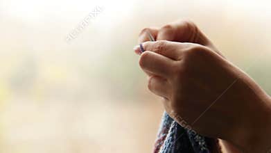 Woman's hands knitting with blurry autumn background