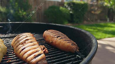 Seasoned chicken breasts grilling on a backyard barbecue