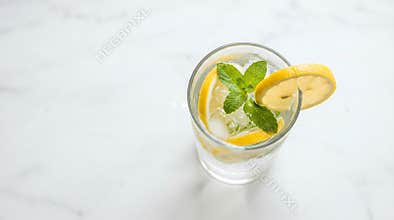 Refreshing clear beverage with ice a vibrant lemon slice and fresh mint leaves presented in a glass