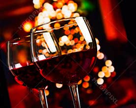 Two red wine glass against christmas lights decoration background