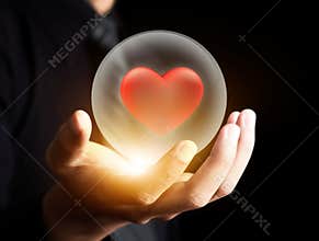 Hand holding red heart in crystal ball