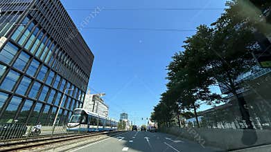 Modern city street with streetcar tracks beside glass office buildings, tree