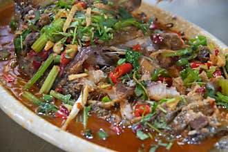 Spicy fish dish with chili, herb, and sauce on ceramic plate