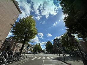Sunny city street with brick buildings, parked bicycles on racks, leafy trees