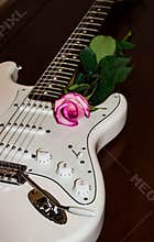 White guitar with a pink rose on the side of soundboard