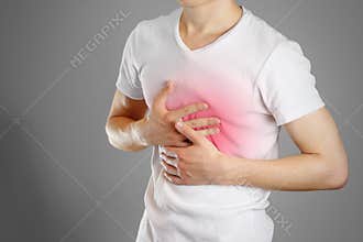 A man holds the Breasts. The pain in his chest. Heartburn.