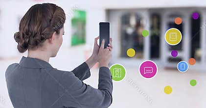 Businesswoman holding mobile phone with apps in shopping mall