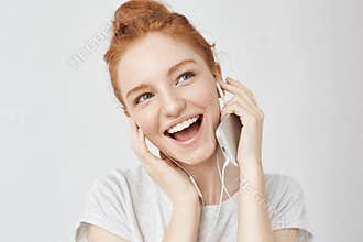 Cheerful foxy girl rejoicing listening music in headphones smiling.