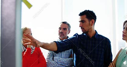 Team of business executives discussing over glass board