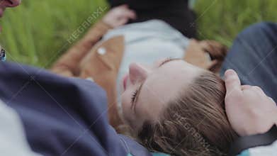 Lovers lie on the meadow and talk. Merry smile.