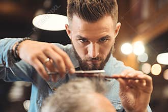 Attentive young barber working in the barbershop