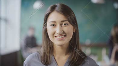 Portrait of attractive Asian businesswoman at loft office. Successful female worker turns, looks around and smiling.