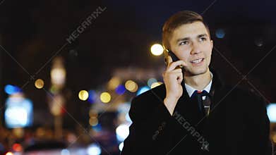 Happy man standing next to the road traffic and talking on cellphone, steadycam shot