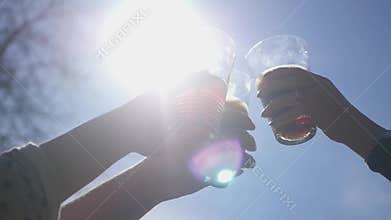 Friends raise glasses on a festive day with various drinks against the blue sky and the bright summer sun. Party in