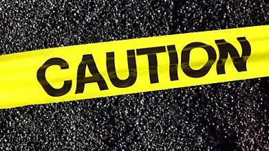 CAUTION Tape Sign Fluttering Above Asphalt