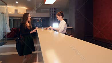 Businesswoman comes to hotel, checking in at a reception desk. 4K.