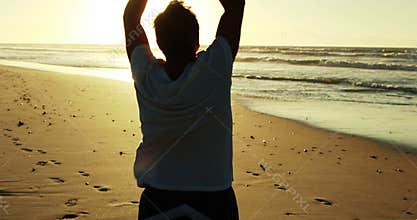 Senior man doing stretching exercise on beach