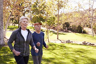 Side View Of Senior Couple Power Walking Through Park