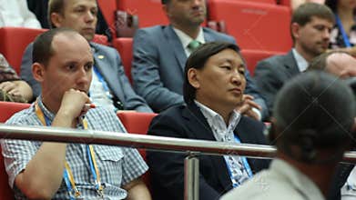 People Sit on Red Chairs in Auditorium and Listen to Lecture