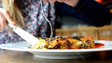 Vegetarian woman eating it lasagne with tempeh and vegetables.