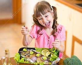 Funny child girl and grilled fish. Healthy eating