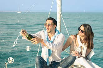 Young couple in love on sailing boat cheering with champagne