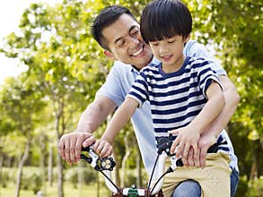 Asian father and son enjoying biking outdoors