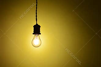 Illuminated hanging led light bulb over orange background