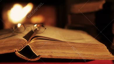 Old book in in front of a fireplace