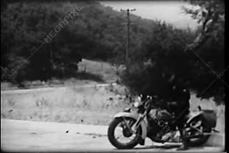 Police officer on motorcycle chasing car on country road